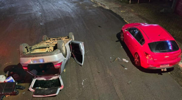 Carro bate em veículo estacionado e capota